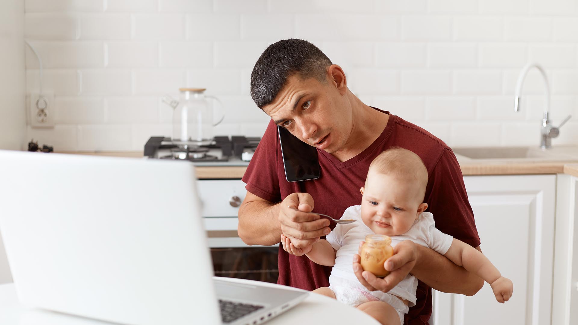 Father feeding child while on the phone
